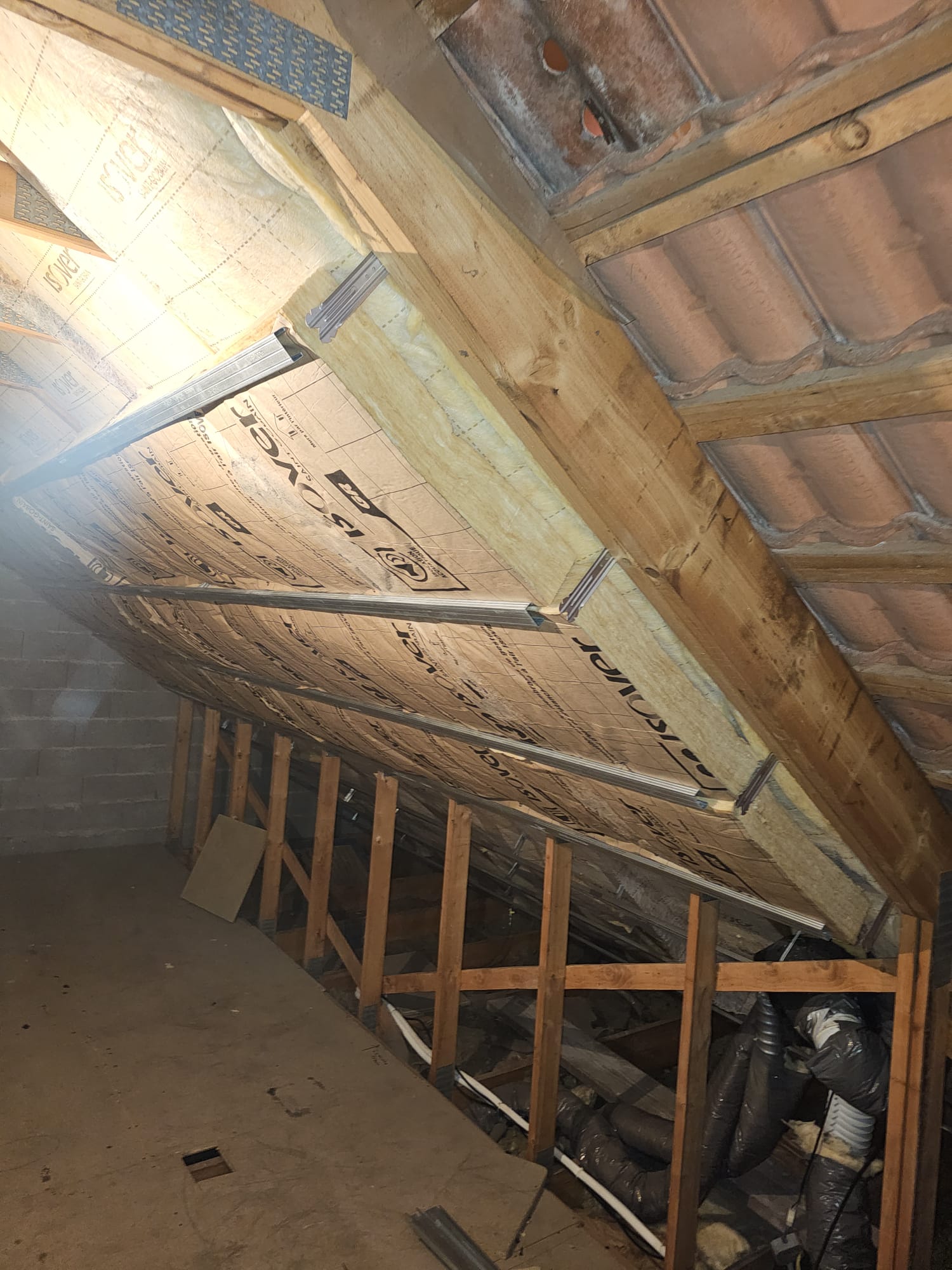 Première couche d'isolation laine de verre entre les poutres